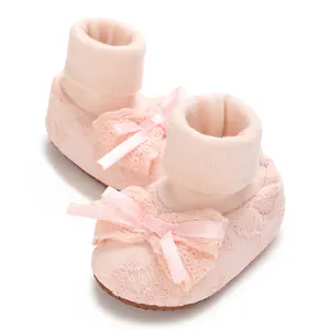Close-up of pink infant baby girl bow sock shoes with lace detail and anti-slip sole