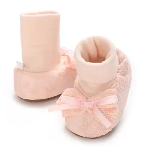 Detailed close-up of soft pink baby pre-walker shoes featuring a lace bow and floral embroidery