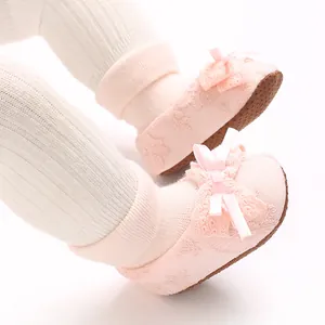 Close-up detail of pink lace baby socks with ribbon bows and non-slip brown soles