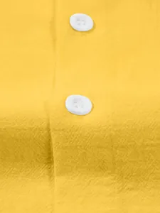 Macro view of a yellow cotton linen shirt showing white buttons and fine fabric texture