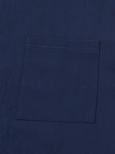 Close-up of navy blue cotton-linen shirt pocket showing fabric texture and fine stitching
