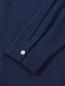 Close-up detail of navy blue cotton linen men's long sleeve shirt cuff with a white button