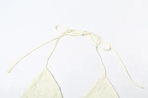 Close-up of cream lace halter top tie strap detail with hollow floral patterns