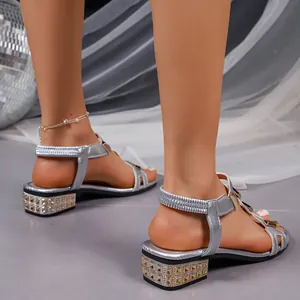 Detailed view of silver Roman sandals featuring rhinestone-studded block heels and straps.
