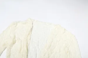Detailed view of the intricate white lace fabric and hollow-out design of the long sleeve top
