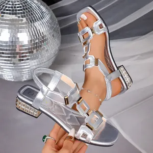 Close-up of silver Roman style flat sandals featuring rhinestone low heels and buckles