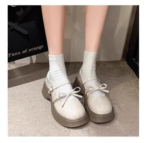 Vista detallada de zapatos Mary Jane crema para niñas con suela gruesa y detalle de lazo