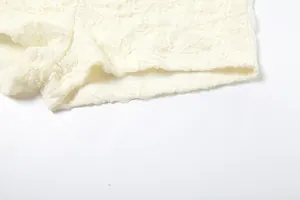 Close-up view of delicate hollow-out cream lace fabric texture on shorts leg opening