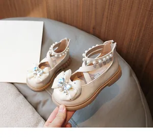 Close-up of girl's beige princess shoes featuring a large bow and pearl ankle straps