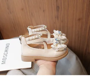 Detail view of cream girls' princess shoes with pearl straps and bow rhinestones