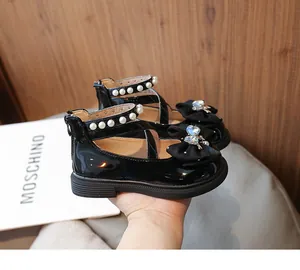 Detail view of black patent leather princess shoes with heart-shaped crystal bow