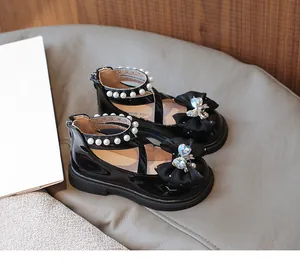 Detail view of girls' black patent leather shoes with bow, pearl accents and back zipper.