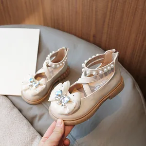 Elegant beige girl's princess shoes featuring a bow and pearl ankle strap details