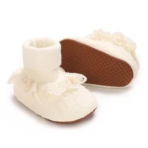 Detalle de zapatos de bebé de encaje blanco con suelas antideslizantes para niñas
