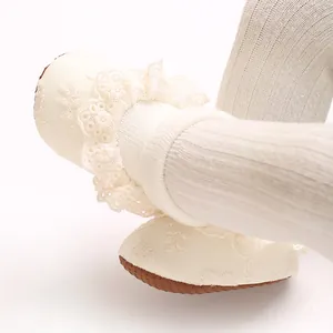Primer plano de delicados calcetines de encaje crema y zapatos suaves para bebés.