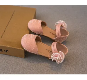 Dettaglio dei sandali rosa in velluto per bambine con fiori di pizzo e perle