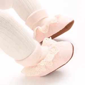 Primer plano de zapatos rosas para bebé niña con volantes de encaje y suela flexible.