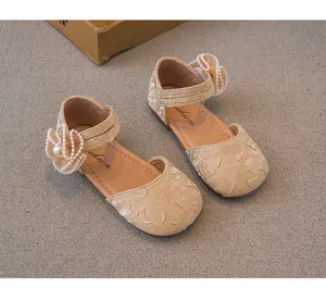 Primo piano di scarpe da principessa beige per bambina con fiori di perle e perline.