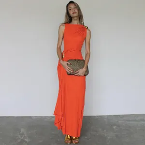Detalle de un vestido largo naranja con adornos metálicos dorados y fruncido