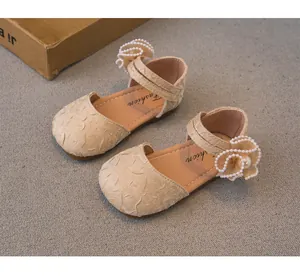 Primo piano di eleganti scarpe da principessa beige per bambina con fiori di perle e trama