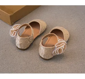 Dettaglio di scarpe da principessa per bambine con elegante decorazione floreale di perle.