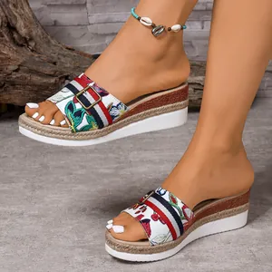 Side view detail of colorful embroidered wedge sandals on feet with anklet accessory