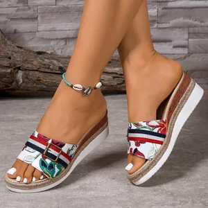 Close-up detail of floral embroidered wedge slides with decorative buckle and rope-wrapped sole