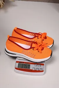 Orange mesh walking shoes on digital scale showing lightweight 375.7g measurement