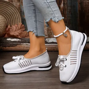 Close-up view of white breathable mesh slip-on sneakers for women on a wooden floor