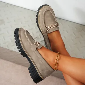 Λεπτομέρεια από γυναικεία loafers σε taupe σουέτ με χοντρή σόλα και χρυσή λεπτομέρεια