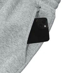 Detailopname van de diepe zijzak van een grijze heren fleece joggingbroek met een zwarte smartphone