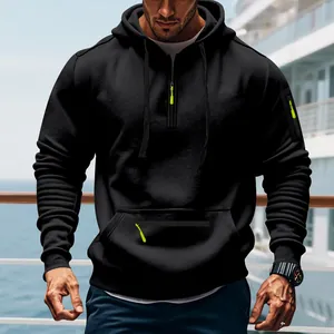 Männliches Model trägt einen schwarzen Kapuzenpullover mit neongrünen Reißverschlüssen