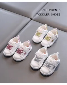 Close-up detailed view of white toddler sneakers with glitter star and velcro straps