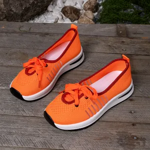 Detail of orange breathable mesh slip-on walking shoes for elderly women on wooden deck