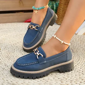 Λεπτομέρεια από μπλε loafers πλατφόρμας με χρυσή αλυσίδα και πολύ χοντρή τρακτερωτή σόλα
