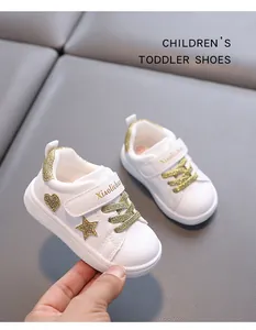 Close-up view of white toddler shoes with gold glitter star and heart pattern details.
