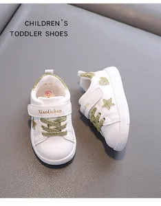 Detailed view of white toddler sneakers featuring gold glitter stars and velcro strap