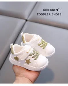 Macro view of white toddler sneakers with gold glitter star and heart pattern details
