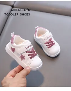 Close-up detail of white toddler shoes featuring pink glitter star and heart accents.
