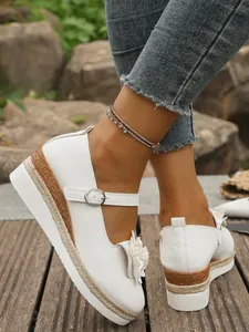 Vista detallada de zapatos de plataforma con cuña blanca, cuerda y adorno floral
