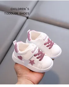 Detailed view of white leather toddler shoes with pink glitter star and heart accents.