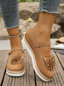 Primer plano de zapatos de cuña marrones con una flor 3D decorativa