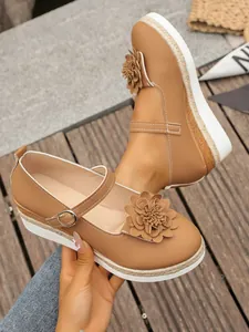 Detalle de zapatos de cuña camel para mujer con flor y suela de cuerda de yute