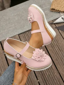 Vista detallada de un zapato Mary Jane rosa con plataforma y adorno floral fino.