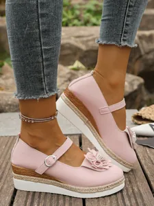 Detalle de zapatos de cuña Mary Jane rosa con flores y suela de plataforma de cuerda