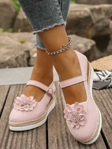 Primer plano de zapatos rosa con cuña, flor en 3D y plataforma de yute trenzado