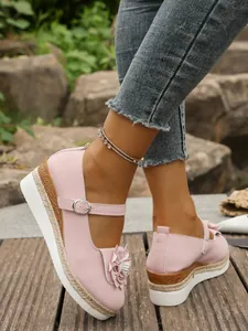 Detalle de zapatos Mary Jane rosa con plataforma, adorno floral y cuña de cuerda