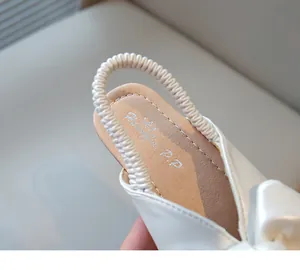 Close-up detail of white girls' bow sandals showing the elasticated heel strap and soft insole.