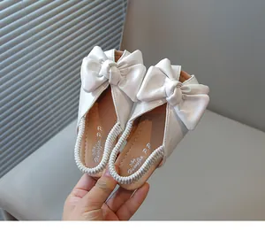 Close-up view of elegant white girls' bow princess sandals featuring an elastic back strap design