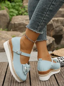 Primer plano de zapatos de cuña azul claro con detalle de flores y suela de cuerda